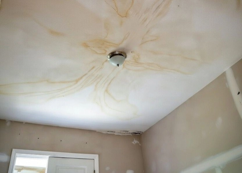 Rainwater leaking through a ceiling and being caught in a container below